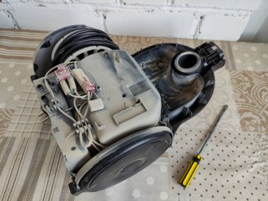 Parçalanmış elektrik süpürgesi ve tornavida masanın üzerinde.