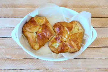 Tahta arka plandaki tepside peynirli poğaça.