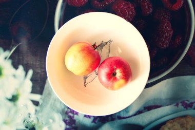 Tabağın üstünde iki olgun elma var.