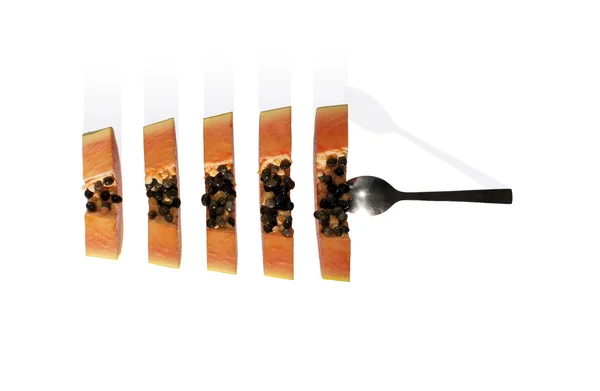 Beyaz izole kaşık ile taze olgun papaya dilimleri. 