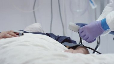 Korunma giysisindeki doktor Coronavirus hastalarının kan basıncını ölçüyor.