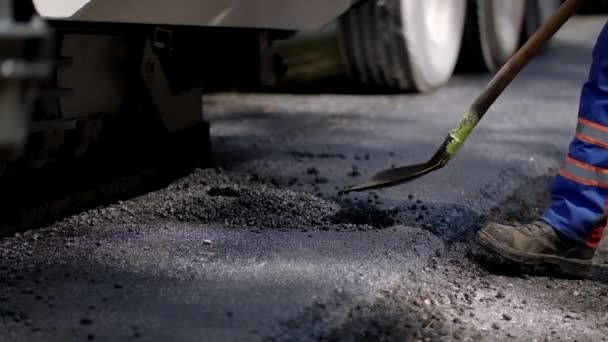 Road Construction Worker Is Shovelling A Small Pile Of Tarmac — Stock Video