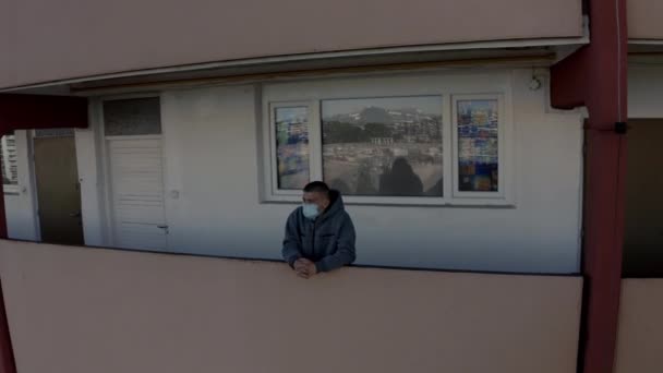 Gioventù caucasica in maschera in piedi su un balcone di alto livello edificio — Video Stock