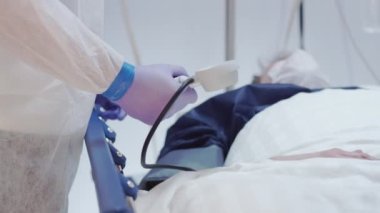 Korunma giysisindeki doktor Coronavirus hastalarının kan basıncını ölçüyor. 