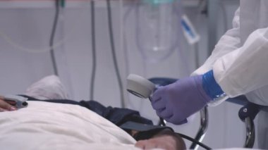 Korunma giysisindeki doktor Coronavirus hastalarının kan basıncını ölçüyor.