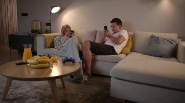 Evde akıllı telefonlarıyla oyun oynayan rekabetçi bir çift. 