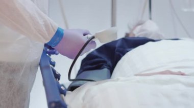 Korunma giysisindeki doktor Coronavirus hastalarının kan basıncını ölçüyor.