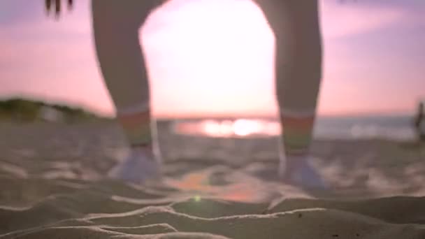 Ung atletisk kvinna gör Burpiees vid solnedgången på stranden — Stockvideo