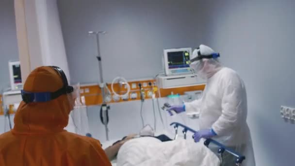 Dokter in een beschermend pak betreedt isolatiekamer met Coronavirus patiënten — Stockvideo