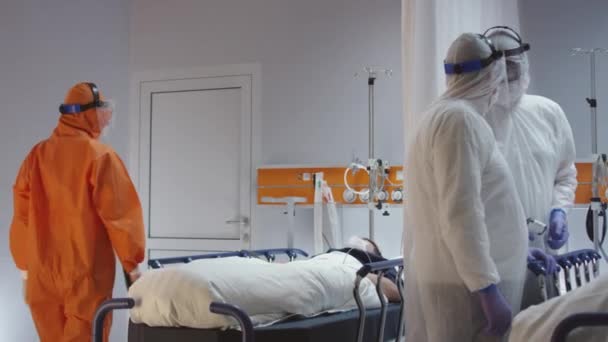 Doctor in Orange Protective Suit Turning On Coronavirus Patients Heart Monitor — Stock Video