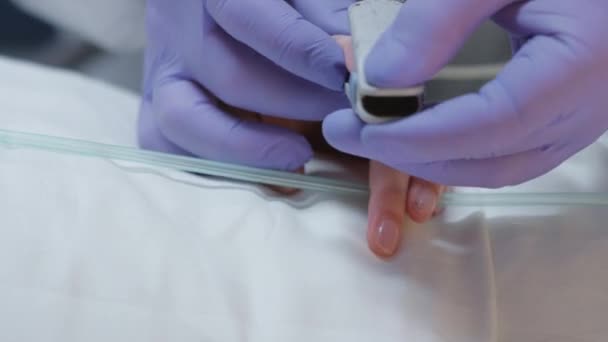 Doutor em terno protetor Puttig no oxímetro em pacientes com coronavírus dedo — Vídeo de Stock
