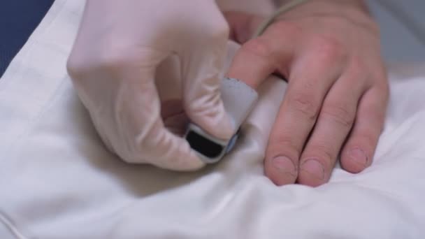 Arzt im Schutzanzug Puttig auf Oximeter am Finger von Coronavirus-Patienten — Stockvideo