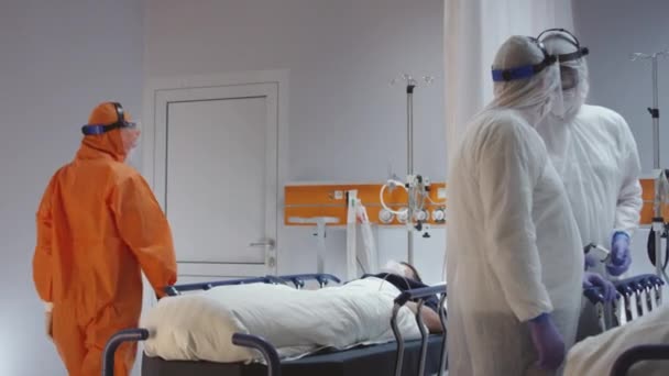 Arzt in orangefarbenem Schutzanzug schaltet Herzmonitor von Coronavirus-Patienten ein — Stockvideo