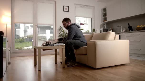 Man probeert een vizier aan die ontworpen is om te beschermen tegen COVID-19 in zijn woonkamer — Stockvideo