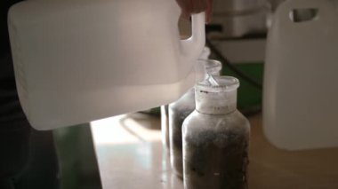 Ağır çekim: Laboratuar teknisyeni cam şişeye arındırılmış su döktü