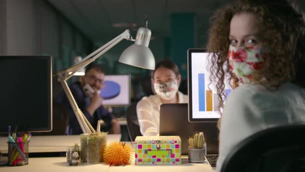Команда молодых профессионалов, работающих допоздна в своем офисе во время пандемии — стоковое видео