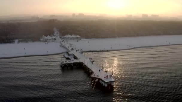 Dech beroucí zimní let nad sněhovou pláží s mola při západu slunce — Stock video