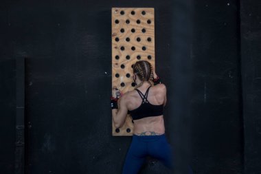 Spor salonunda maske takan kız Cross antrenmanı yapıyor.