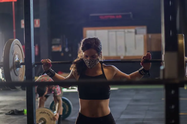 girl with mask in a gym doing cross training