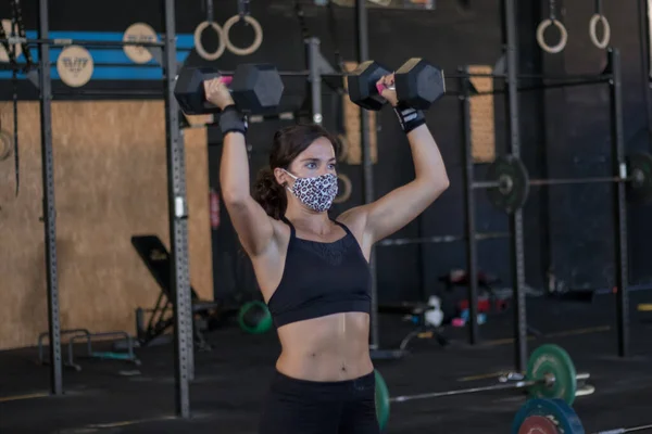 girl with mask in a gym doing cross training