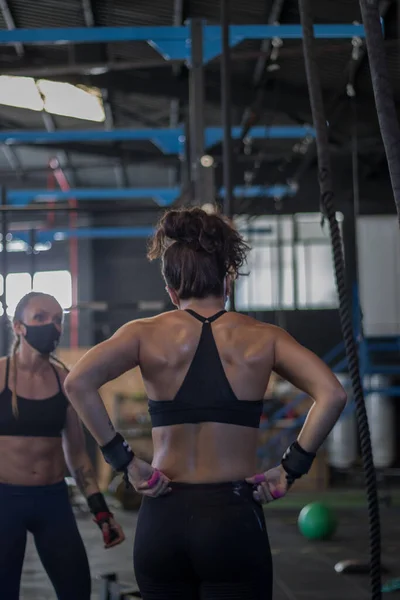 Girls with masks in a gym doing Cross training, rope climb