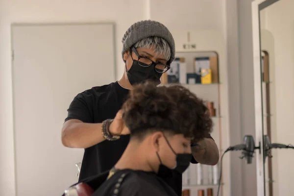 流行の時にマスクで男の子の髪を切断マスクを持つ若い美容室でのセッション — ストック写真