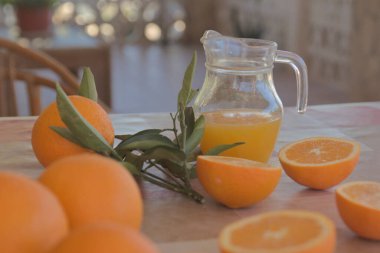 Doğa ile çevrili bir kır evi masasının üzerinde portakal suyu dolu cam sürahi.