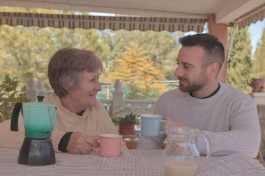 Anne ve oğlu, doğayla çevrili bir kır evinin terasında İtalyan bir kahve makinesiyle yapılan lezzetli kahvenin tadını çıkarıyorlar.