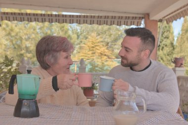 Anne ve oğlu, doğayla çevrili bir kır evinin terasında İtalyan bir kahve makinesiyle yapılan lezzetli kahvenin tadını çıkarıyorlar.