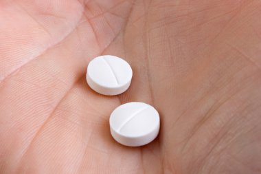 Hand with two medicine pills clipart