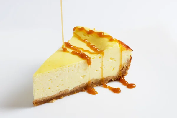 Stück Käsekuchen mit einer dünnen Karamellsoße übergießen — Stockfoto