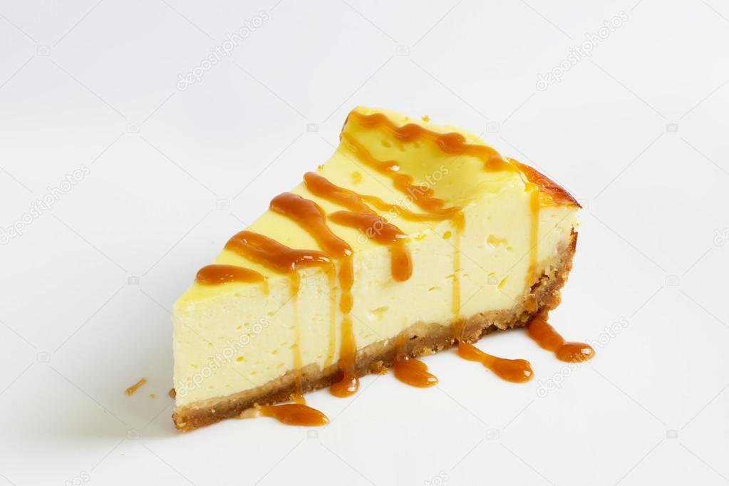 Slice of cheesecake topped with caramel sauce isolated