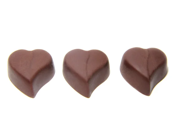 Tre caramelle al cioccolato a forma di cuore su sfondo bianco — Foto Stock