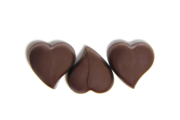 Tres dulces de chocolate en forma de corazón sobre fondo blanco —  Fotos de Stock