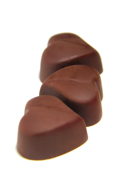 Tre caramelle al cioccolato a forma di cuore su sfondo bianco — Foto Stock