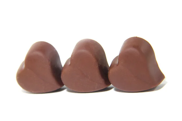 Три шоколадні цукерки у формі серця на білому тлі — стокове фото