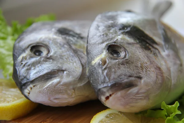 Dorado fresco en tabla de cortar con limón y verduras —  Fotos de Stock