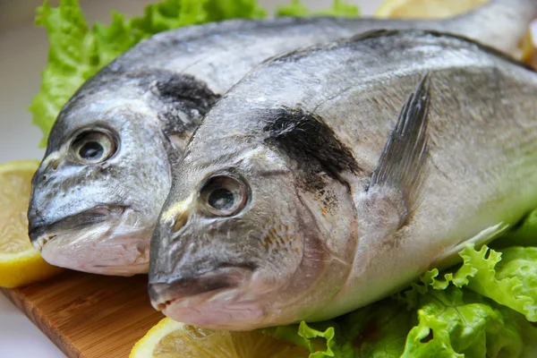 Dorado fresco en tabla de cortar con limón y verduras —  Fotos de Stock