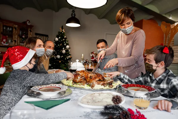 家族はコロナウイルスの年に自宅でクリスマス感謝祭のテーブルを集めました 家族は新しい健康規制を遵守するために外科マスクを着用しています 新しい規則隔離封鎖 — ストック写真