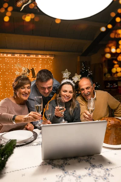 スカイプビデオ通話を使用して新年の前夜に 家族や友人をシャンパングラスで迎える幸せな家族 親戚はノートパソコンに手を振っている コロナウイルスのパンデミックの間の社会的距離 — ストック写真
