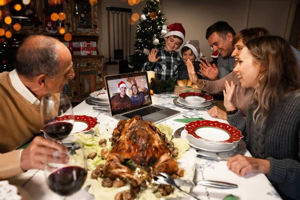 A couple on a screen and some relatives celebrating Christmas using a video call. People greeting their family and friends on Christmas eve online. Social distancing, self isolation quarantine.