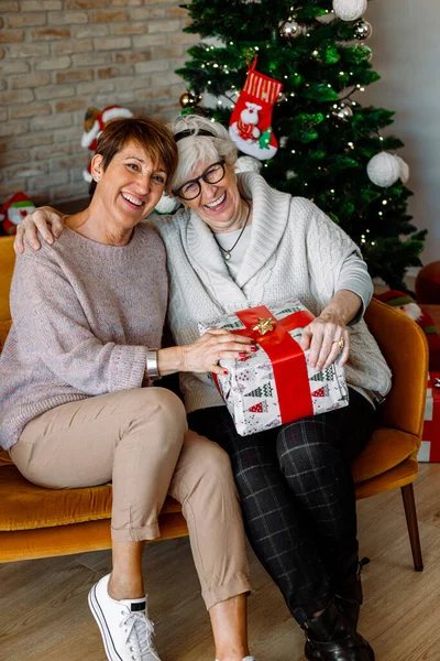 Alegre Ancianas Emocionadas Sentadas Sofá Sala Estar Intercambiando Regalos Navidad —  Fotos de Stock