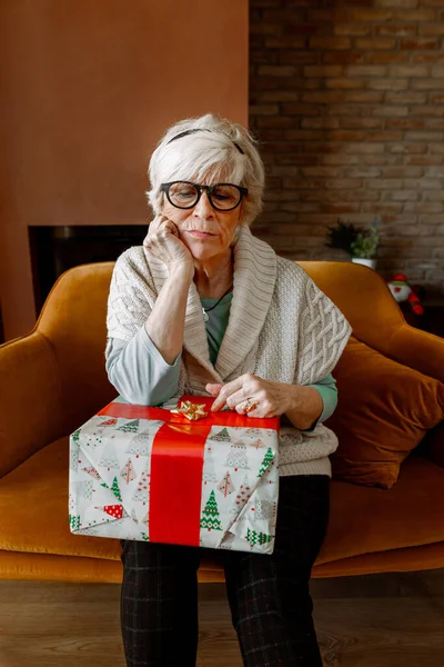 Портрет Грустной Скучающей Пожилой Женщины Сидящей Одиночестве Диване Обернутым Подарком — стоковое фото