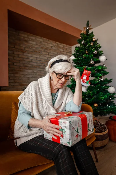 包装されたギフトと1人暮らしの部屋に座っている悲しい年上の女性を落ち込ませました クリスマスのコロナウイルスのパンデミックの間の自己分離での悲しみ Covid隔離 ロックダウン — ストック写真
