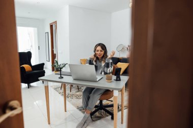 Modern rahat ofis ve oturma odasında masa başında oturan 30 'lu yaşlarda serbest çalışan bir genç. Kulaklık takan öğrencinin bilgisayarında video kaydı var. Uzaktan kumandalı. Coronavirus Karantinası.