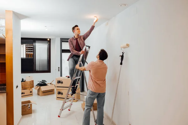 Young Man Stairway Changing Light Bulb While His Friend Helps — Stock Photo, Image