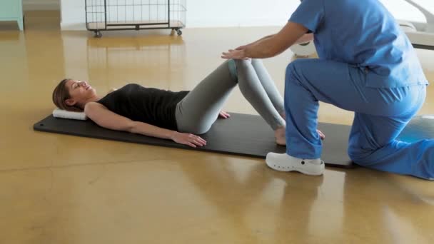 Female Patient Lying Mat Exercising Her Physiotherapist Using Resistance Band — Stock videók