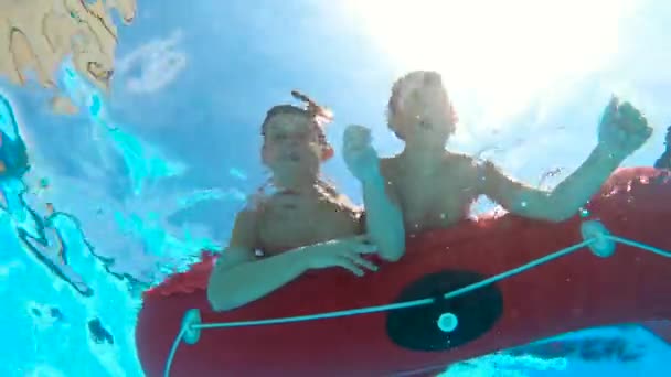 水中から撃たれた 2人の少年は 水に入るために深呼吸をし カメラを見て手を振って 澄んだ水の中で太陽と青い空とダイビングを楽しんでいます 4Kスローモーション — ストック動画