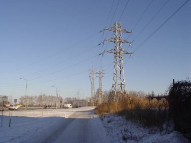 Arkasında elektrik hatları ve evler olan kış endüstriyel şehir manzarası