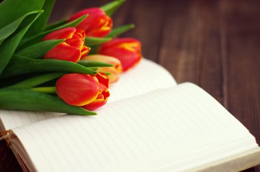 Tulip buket ve koyu ahşap plakalar üzerinde açık boş defter.